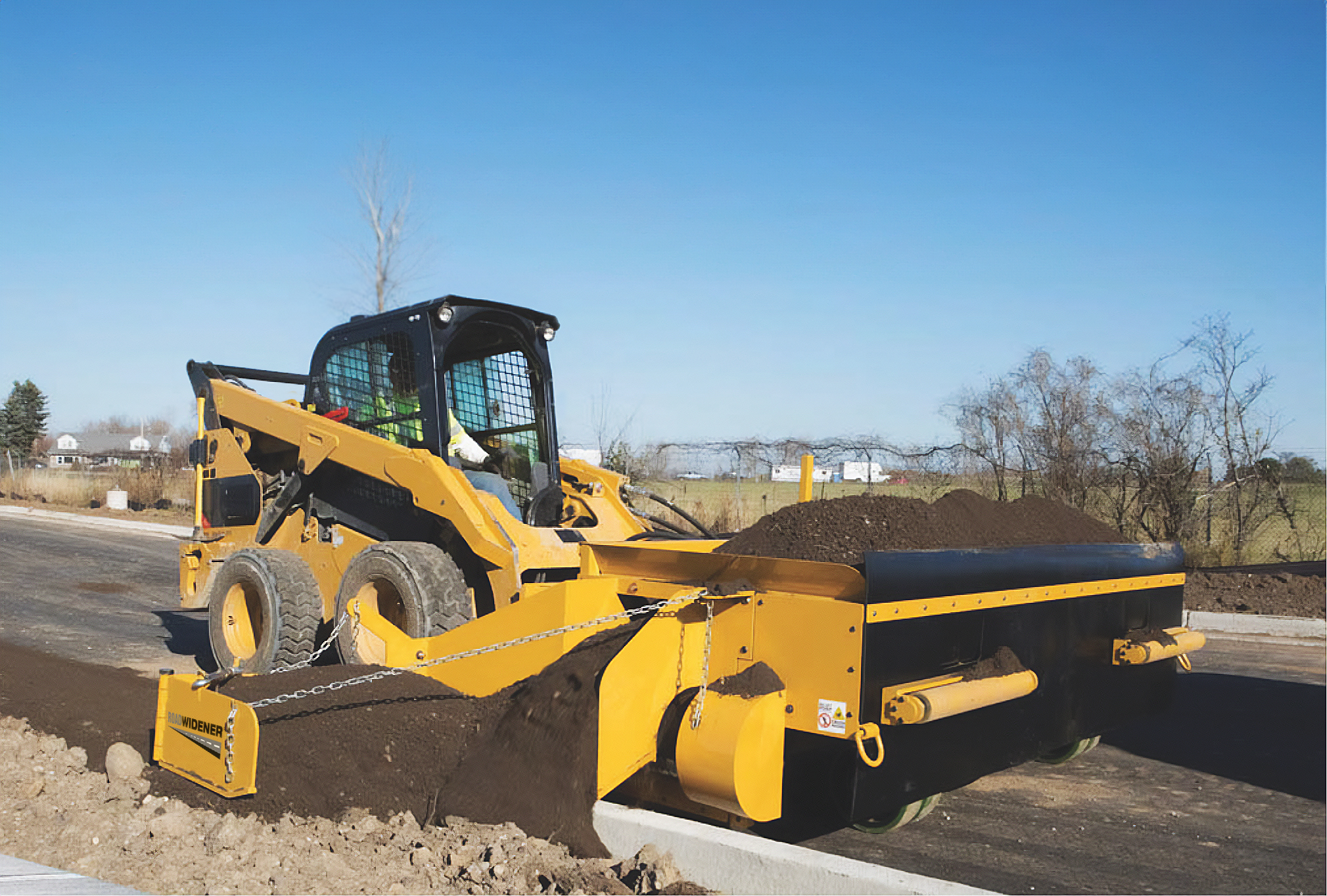 The Curb Backfiller accessory keeps new curbs intact with a protective wheel that prevents the accessory from scraping against the curb (image courtesy of Road Widener)