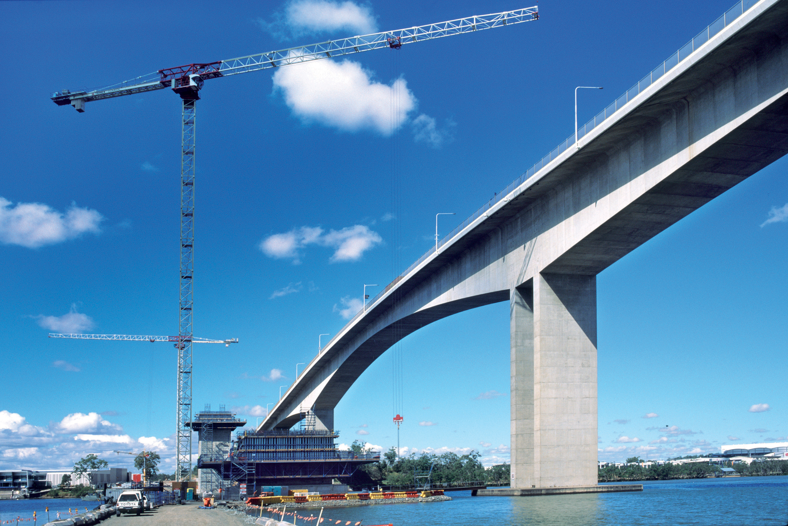 Unusually an exact impression of the eventual bridge stands alongside the rising concrete - the original Gateway bridge built 20 years ago Brisbane bridge