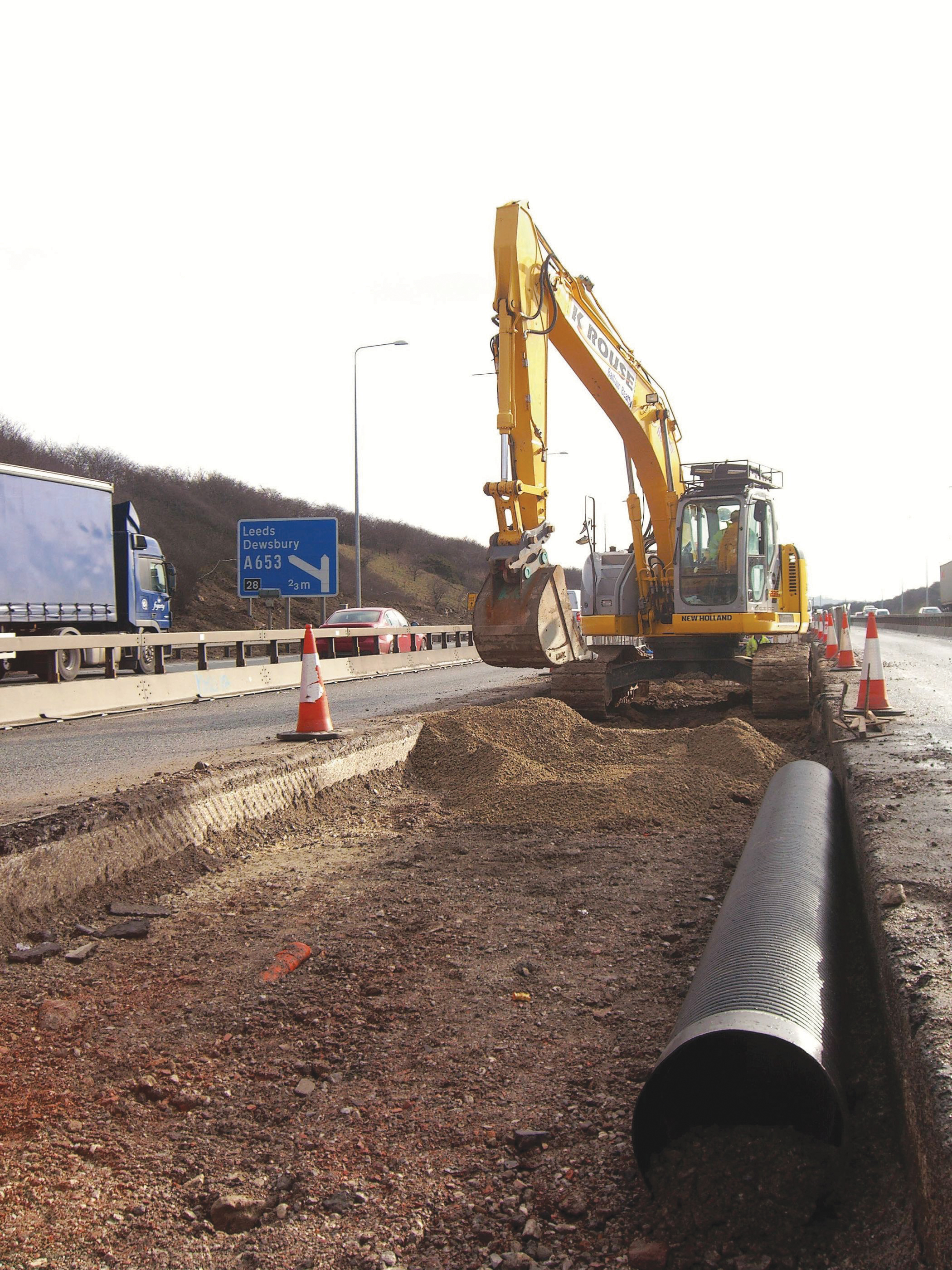A New Holland E235B reduced tailswing tracked excavator at work on the motorway A New Holland E235B reduced tailswing tracked excavator at work on the motorway