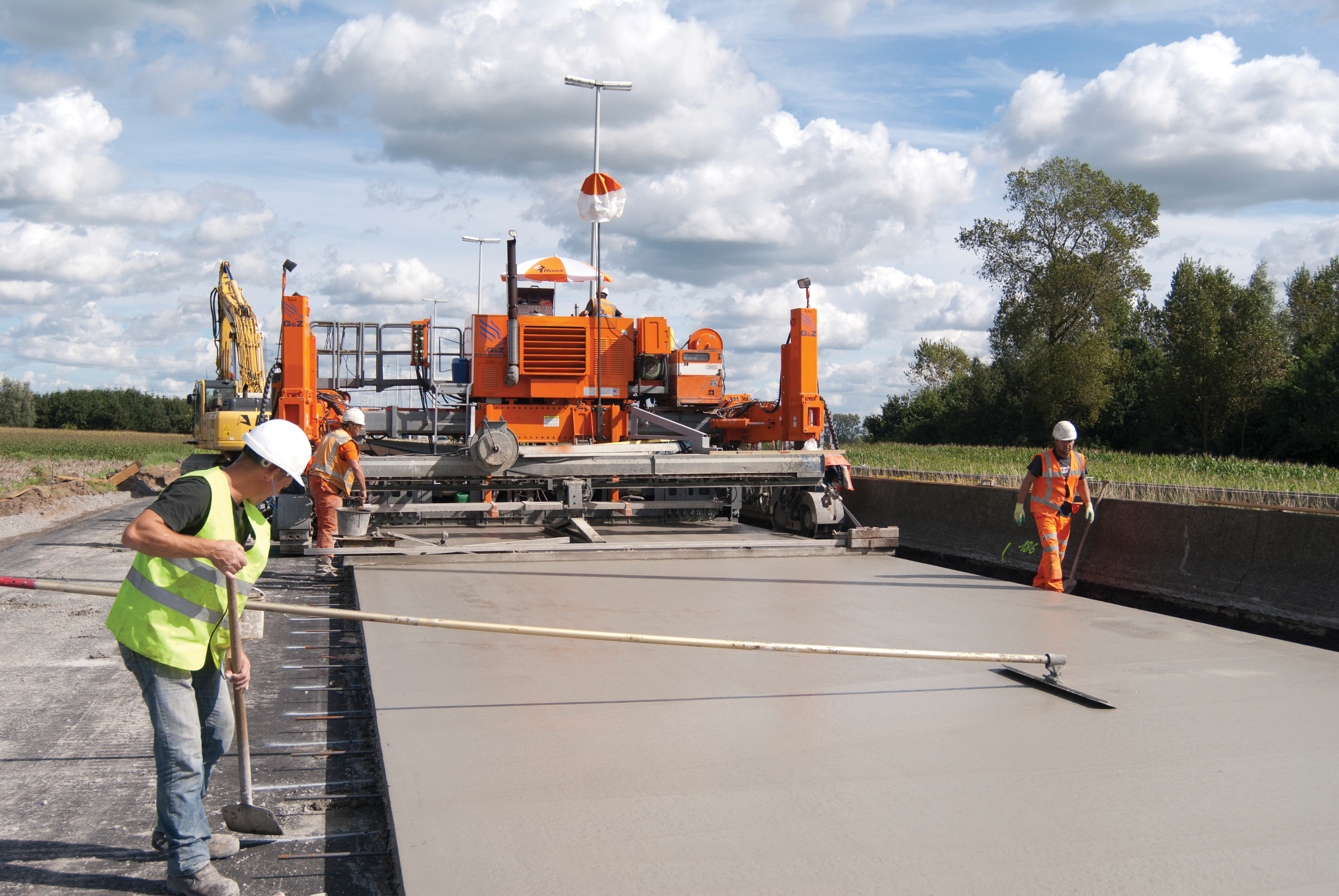 The Roos team produce an incredibly smooth finish , working at a rate of around 1km per day in two shifts. team flatening concrete