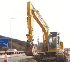A New Holland E235B reduced tailswing tracked excavator at work on the motorway 