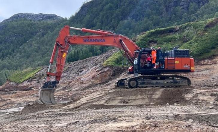 Transport Minister Jon-Ivar Nygård at the controls of an excavator, helped by a Skanska employee, on site of the E10 Tjeldsund-Gullesfjordbotn-Langvassbukt road project (image courtesy Erik Betten/State Road Administration)